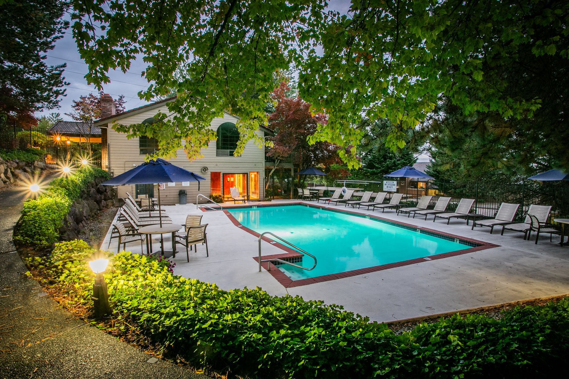 Courtyard pool at dusk with lounge chairs, umbrellas — multi-family photography