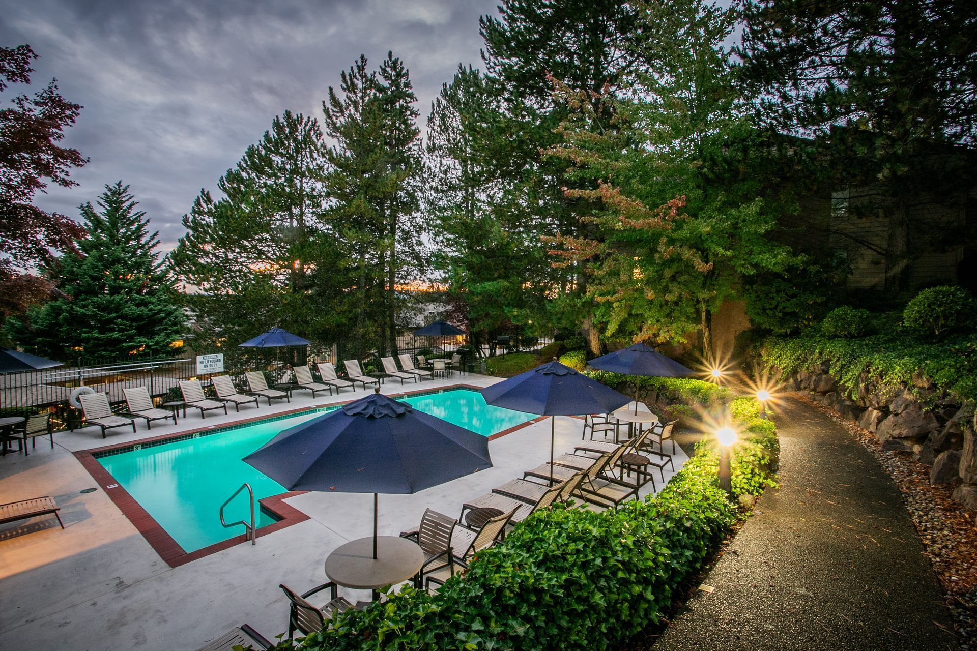 Lit hotel pool at dusk with lounge chairs, umbrellas — Las Vegas multi-family photography