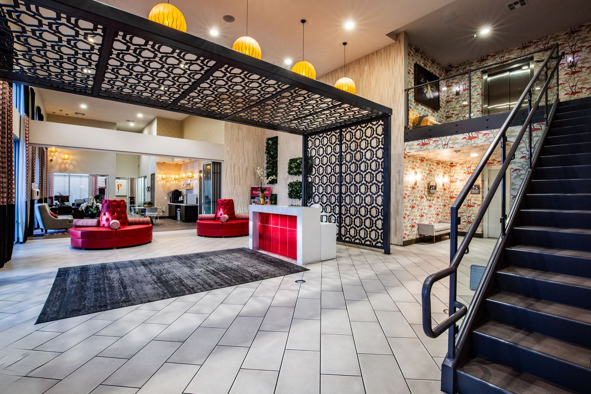 Modern hotel lobby with black staircase, white tiled floor, red seating — multi-family photography
