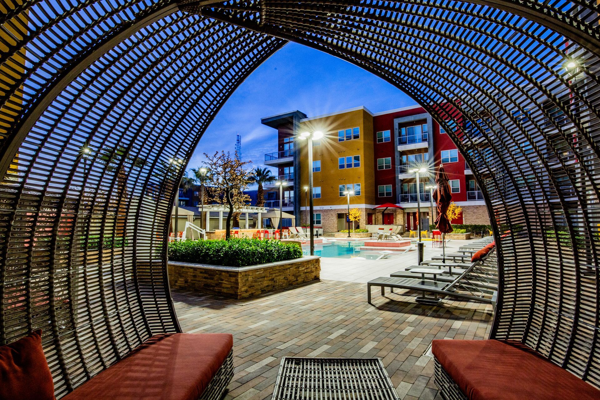 Curved metal canopy framing a lit courtyard with benches and colorful — multi-family photography