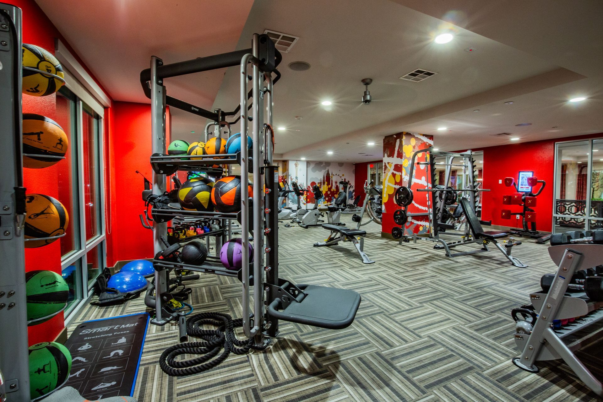 Bright red gym with exercise machines, weight racks, and patterned flooring — commercial multi-family property photography