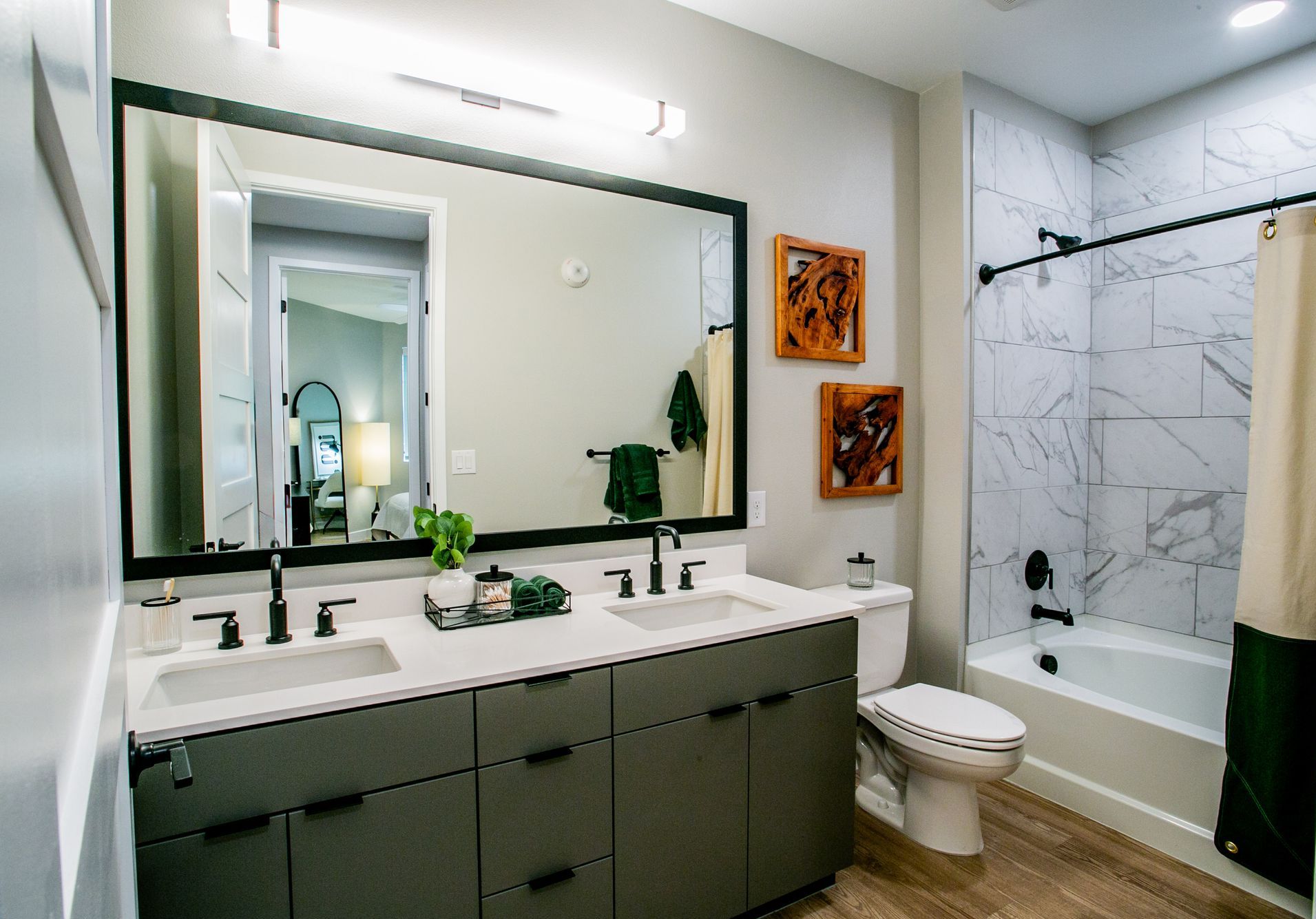 Modern bathroom with double vanity, large mirror, toilet, and tiled shower tub combo — Las Vegas commercial multi-family property photography