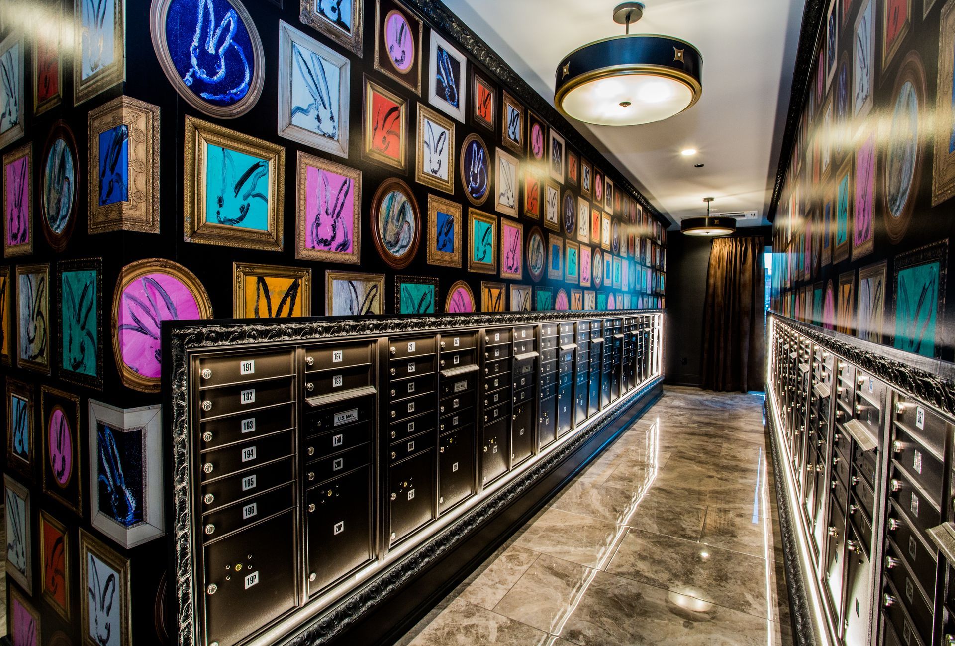 Colorful framed art lining a sleek hallway with black cabinets and marble floors — Las Vegas commercial multi-family property photography