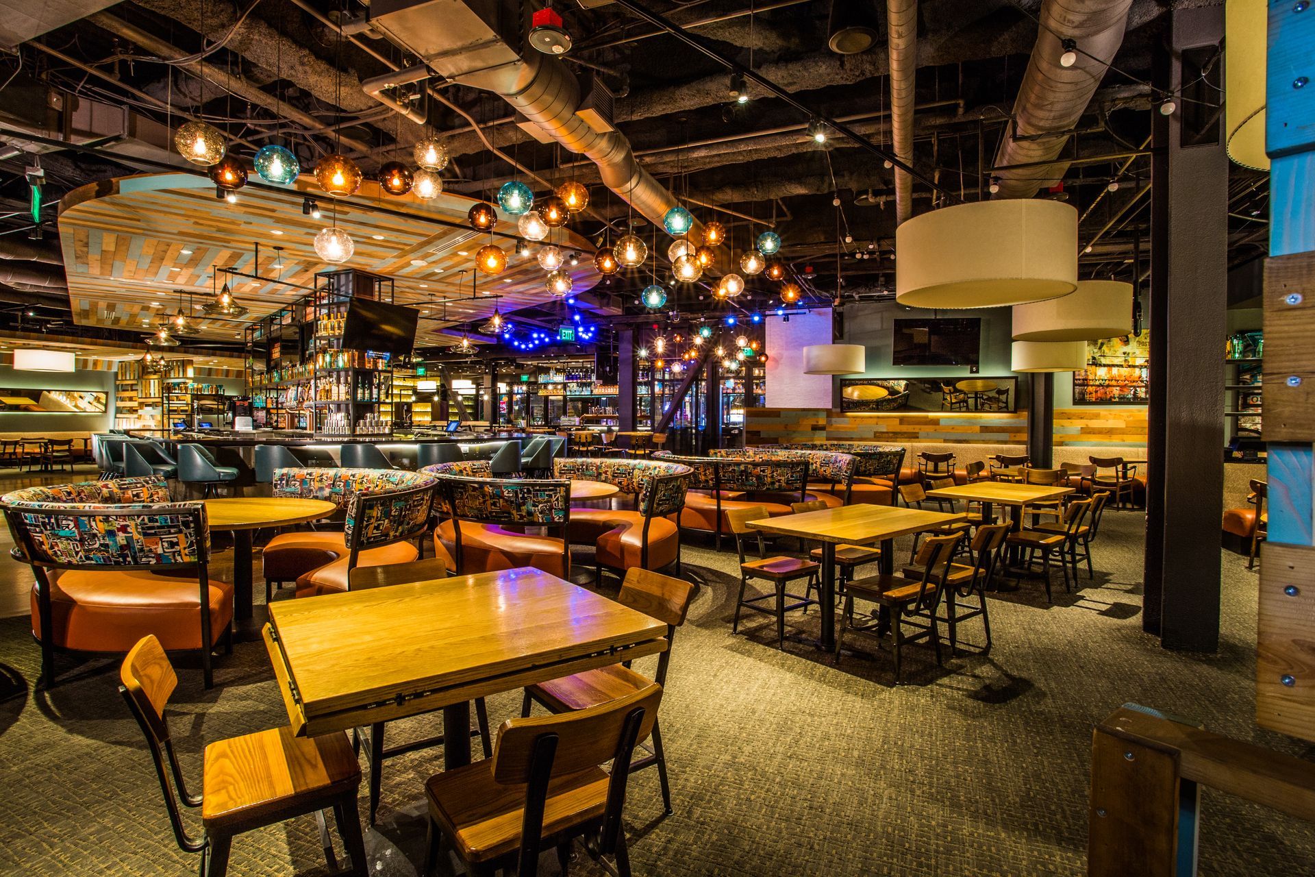 Dimly lit modern restaurant with wooden tables, bar seating — multi-family photography