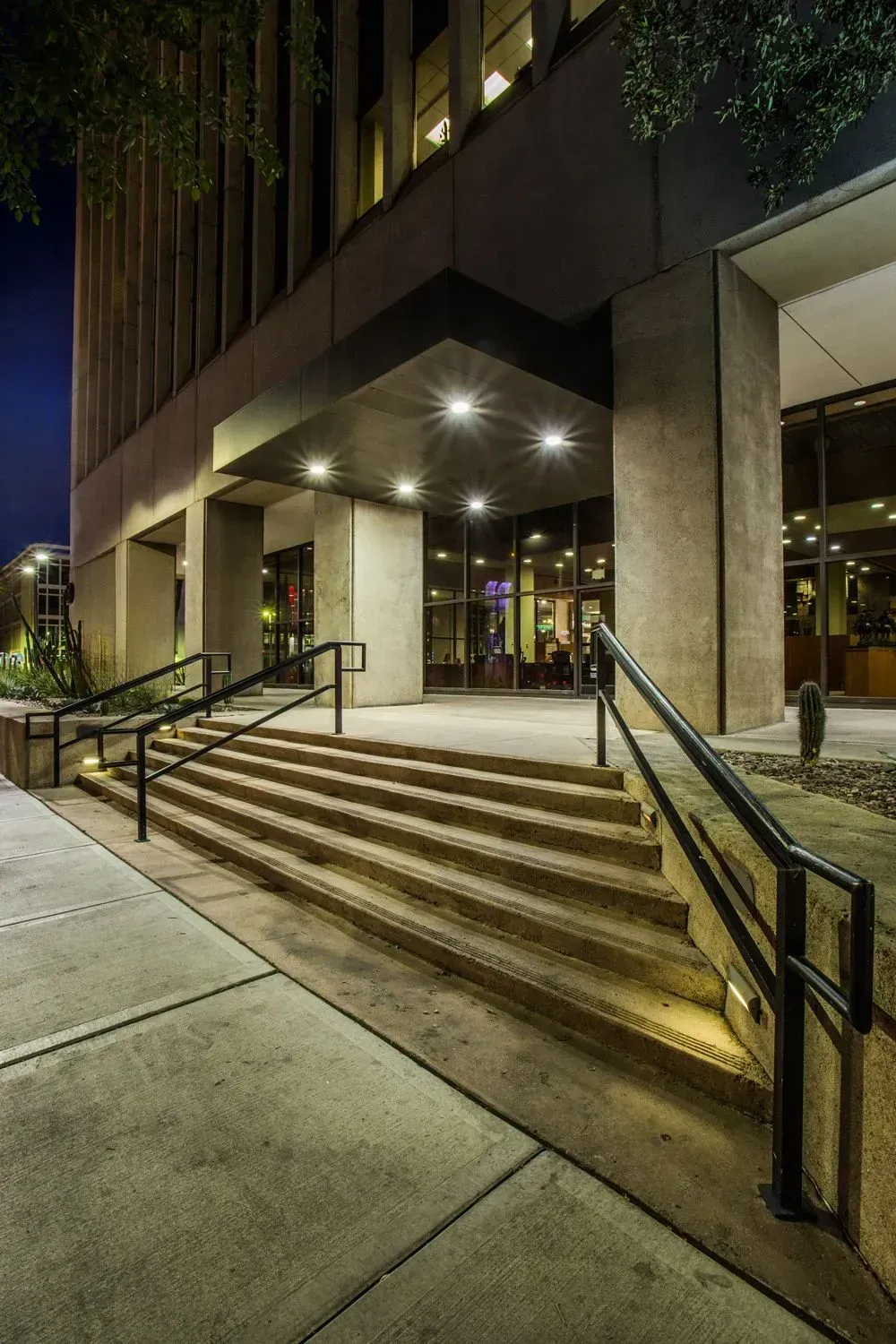Building entrance with lit steps, black railings, and glass doors at night — Las Vegas professional photography