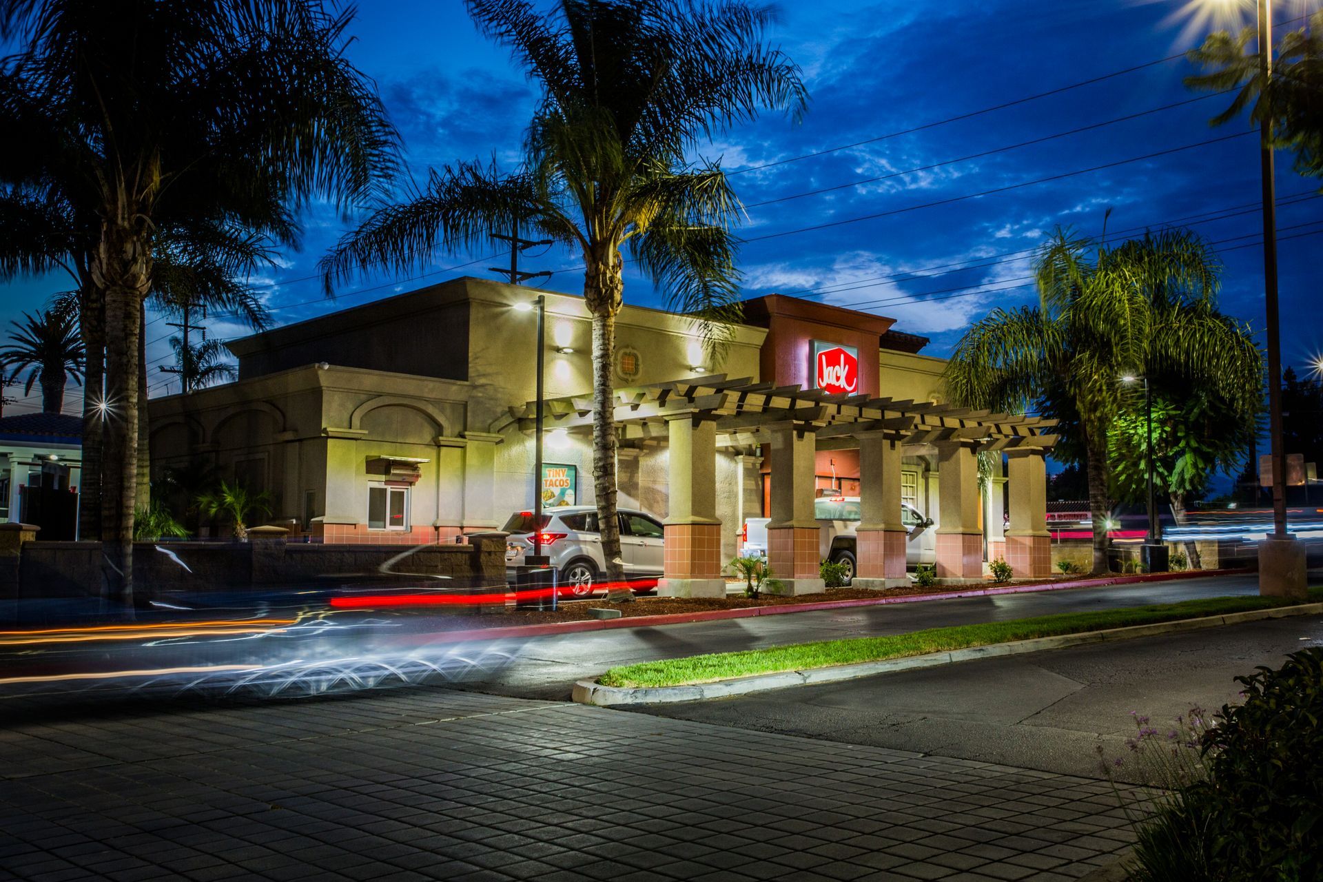 Night view of a lit building with palm trees and light trails from — multi-family photography