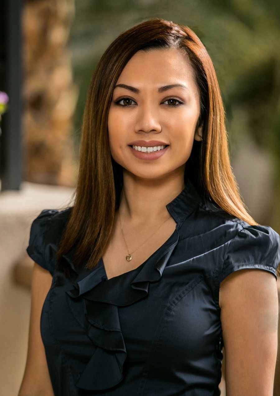 Woman in a black blouse smiling outdoors with a blurred garden background — Las Vegas portrait photography