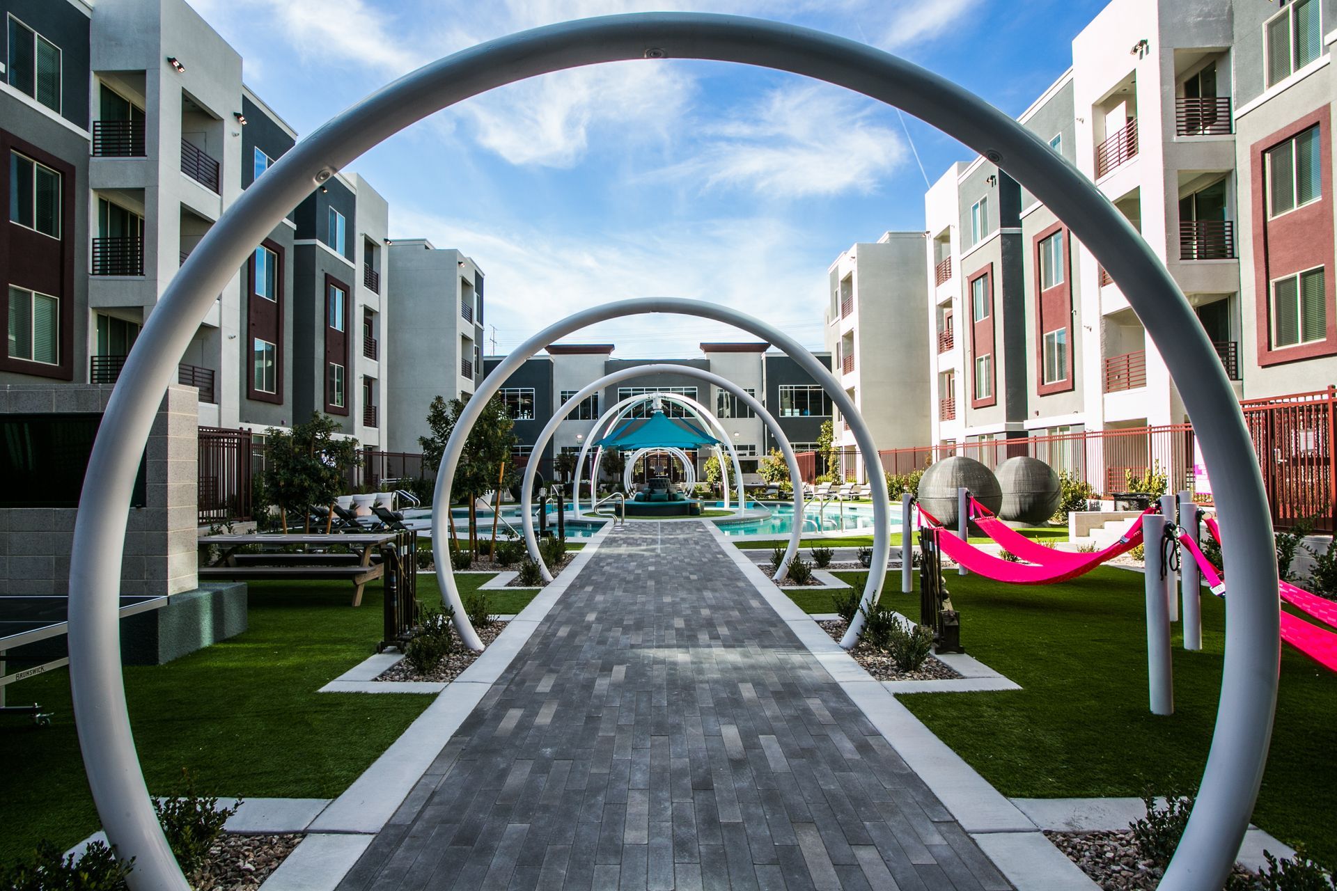 Modern apartment courtyard with circular sculptures, central walkway, and colorful hammocks — Las Vegas commercial multi-family property photography