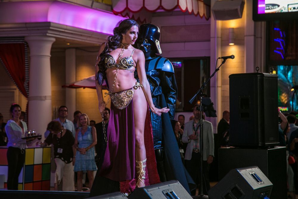Costumed performers on a stage at a nightclub, one in a gold outfit and one in a black armored suit