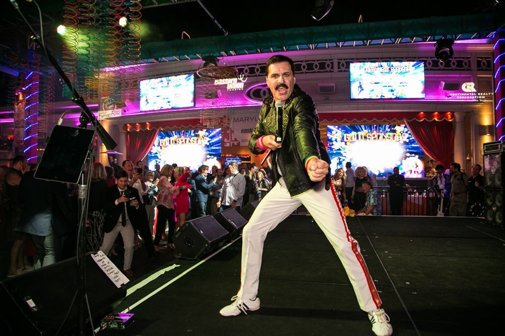 Singer on a neon-lit stage, posing in a black jacket and white pants — Las Vegas event photography