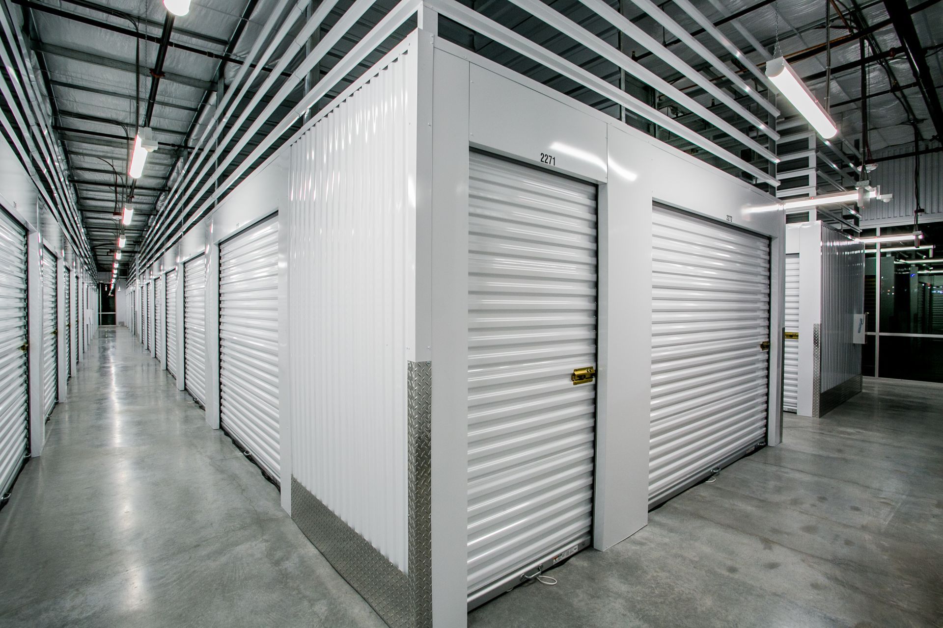Interior of a clean self-storage facility with white roll-up unit doors — multi-family photography