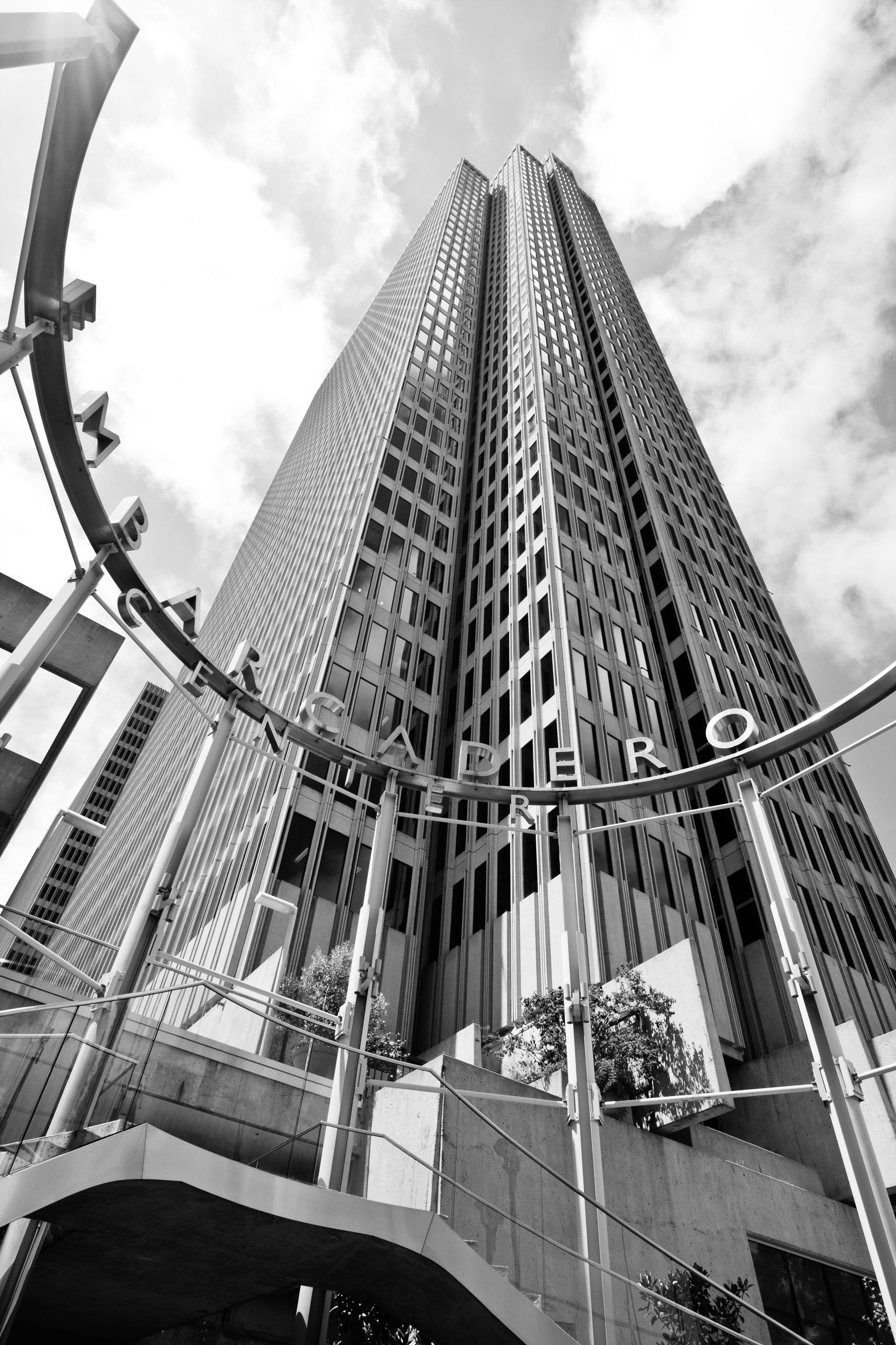 Skyscraper viewed from below through a curved entrance gate under a cloudy sky — Las Vegas architectural photography