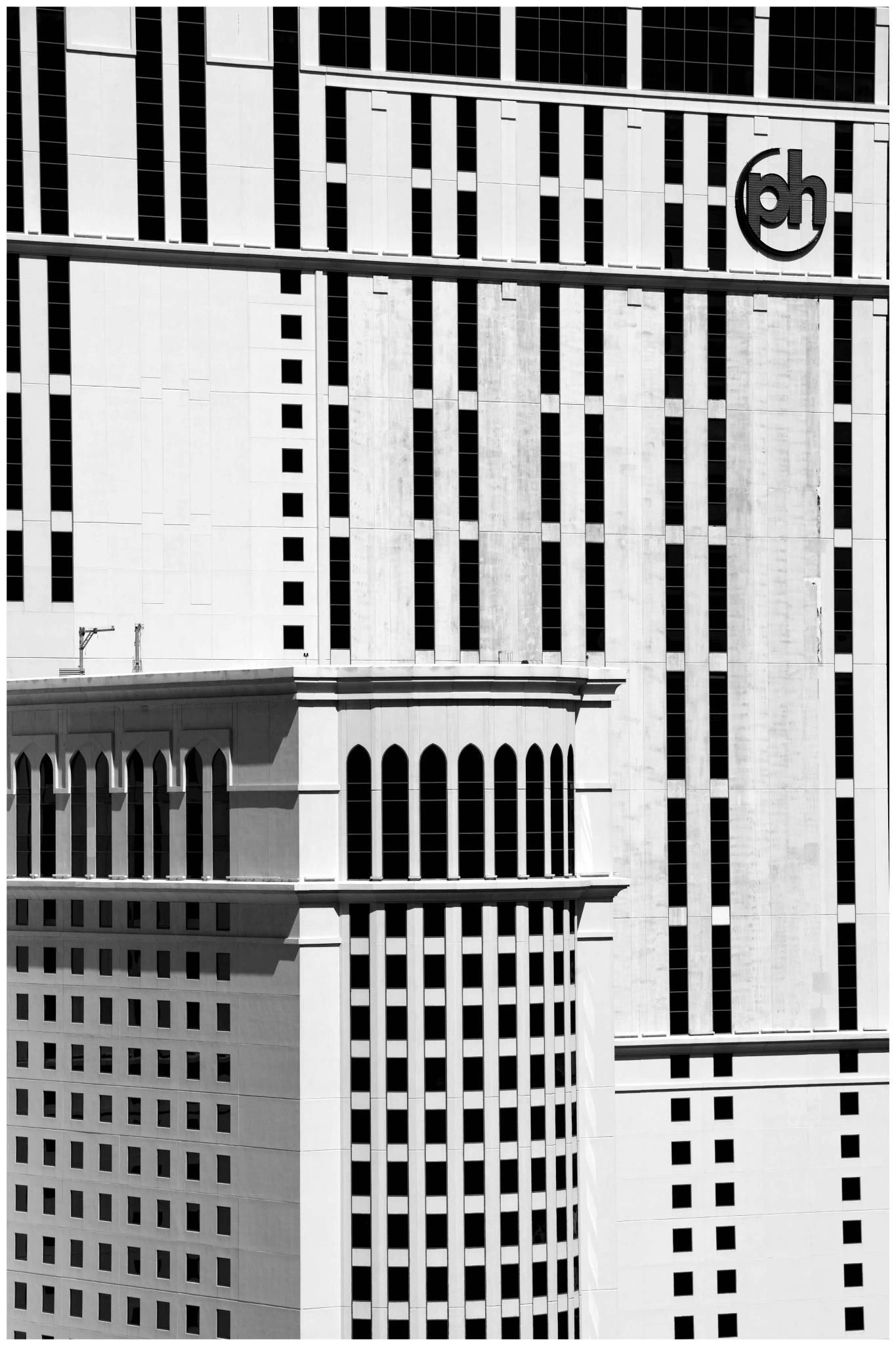 Black-and-white city buildings with striped facades and a circular logo near the top — architectural photography