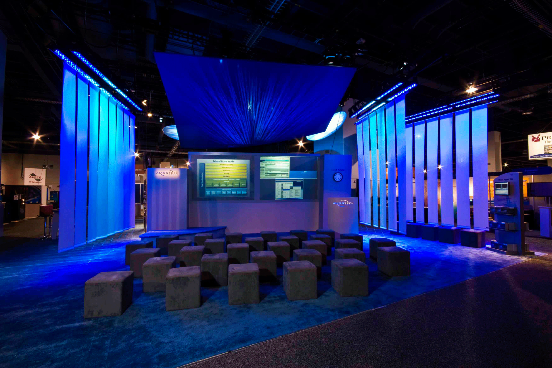 Blue-lit event stage with screens, curtains, and rows of cube stools in a dark venue — Las Vegas professional photography