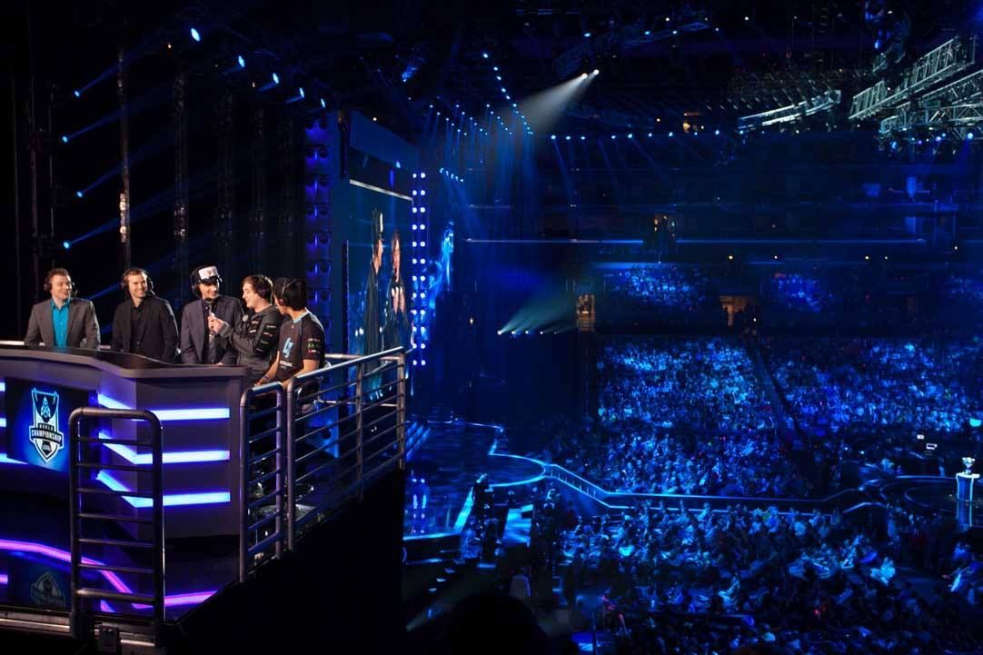 Panelists on a lit stage overlooking a packed blue-lit arena during a live event — Las Vegas convention and event photography