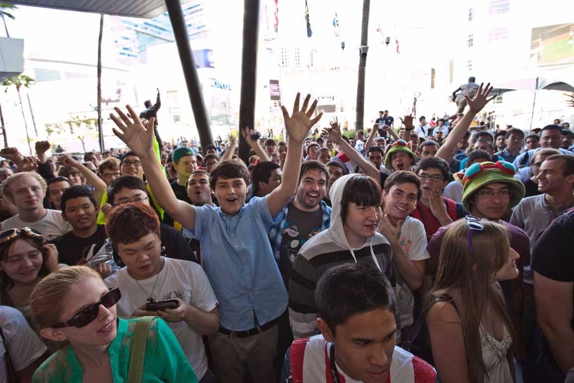 Crowd at an outdoor event with people raising their hands and smiling under a tent — convention and event photography