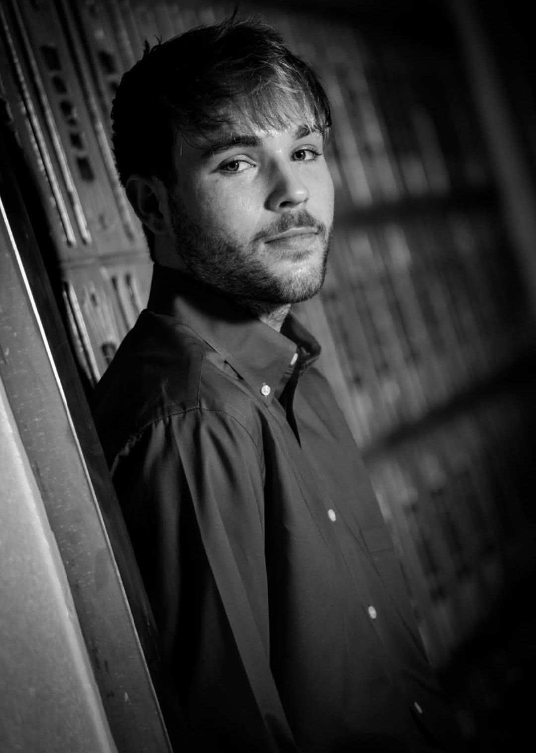 Black-and-white portrait of a man leaning against a wall, looking at the camera — Las Vegas portrait photography