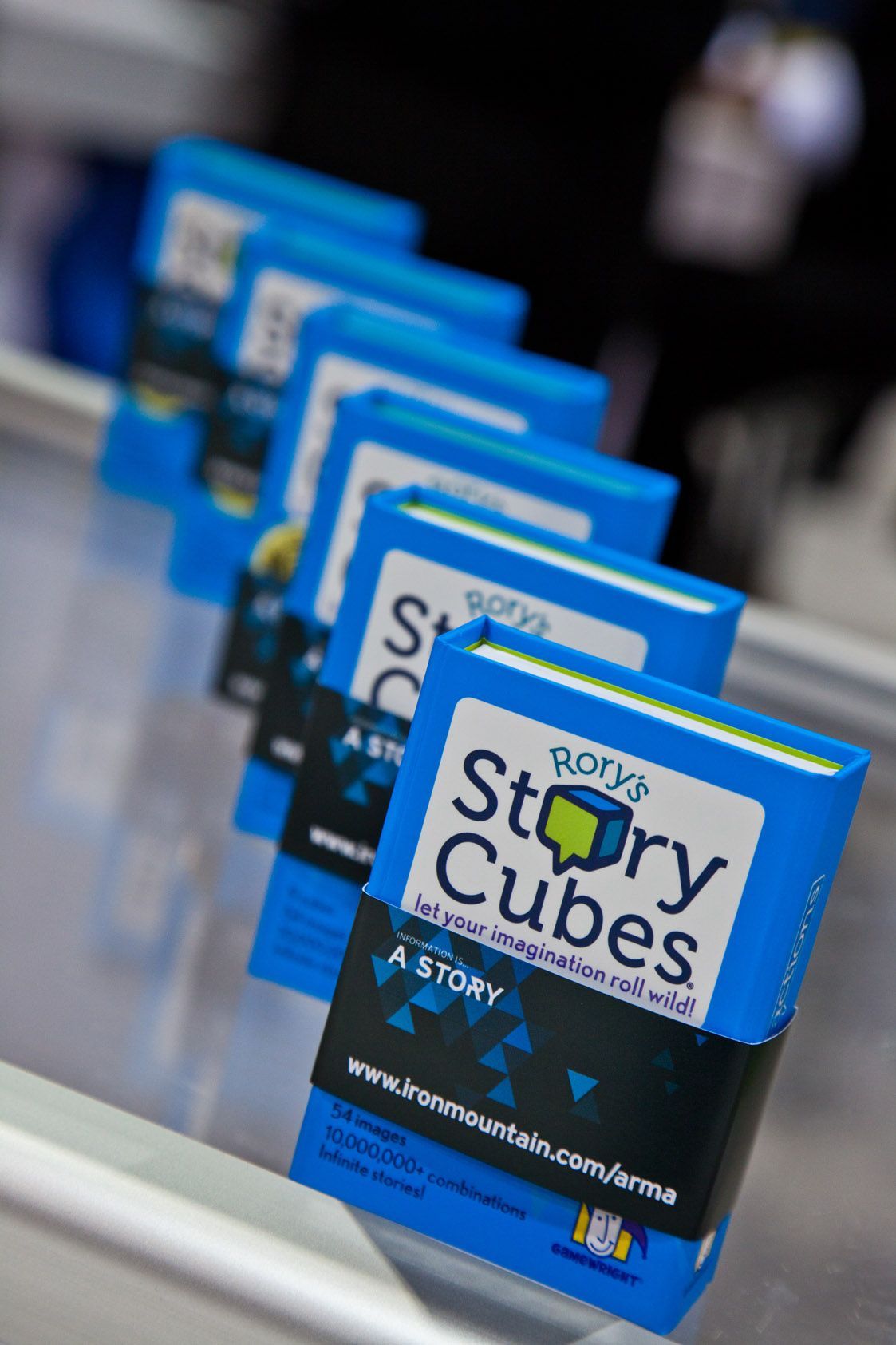 Blue “Story Cubes” game boxes lined up on a display shelf — Las Vegas convention and event photography