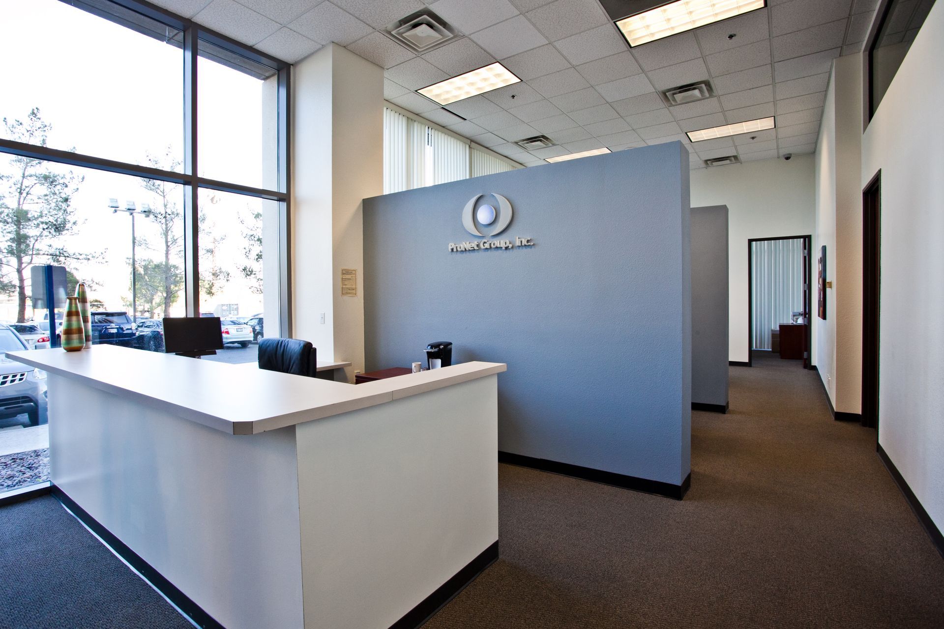 Modern office lobby with reception desk, blue partition walls, and large windows