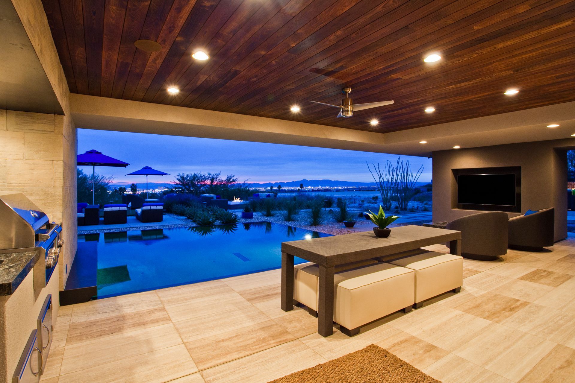 Luxury patio with pool, sunset view, wooden ceiling, and modern outdoor seating — real estate photography