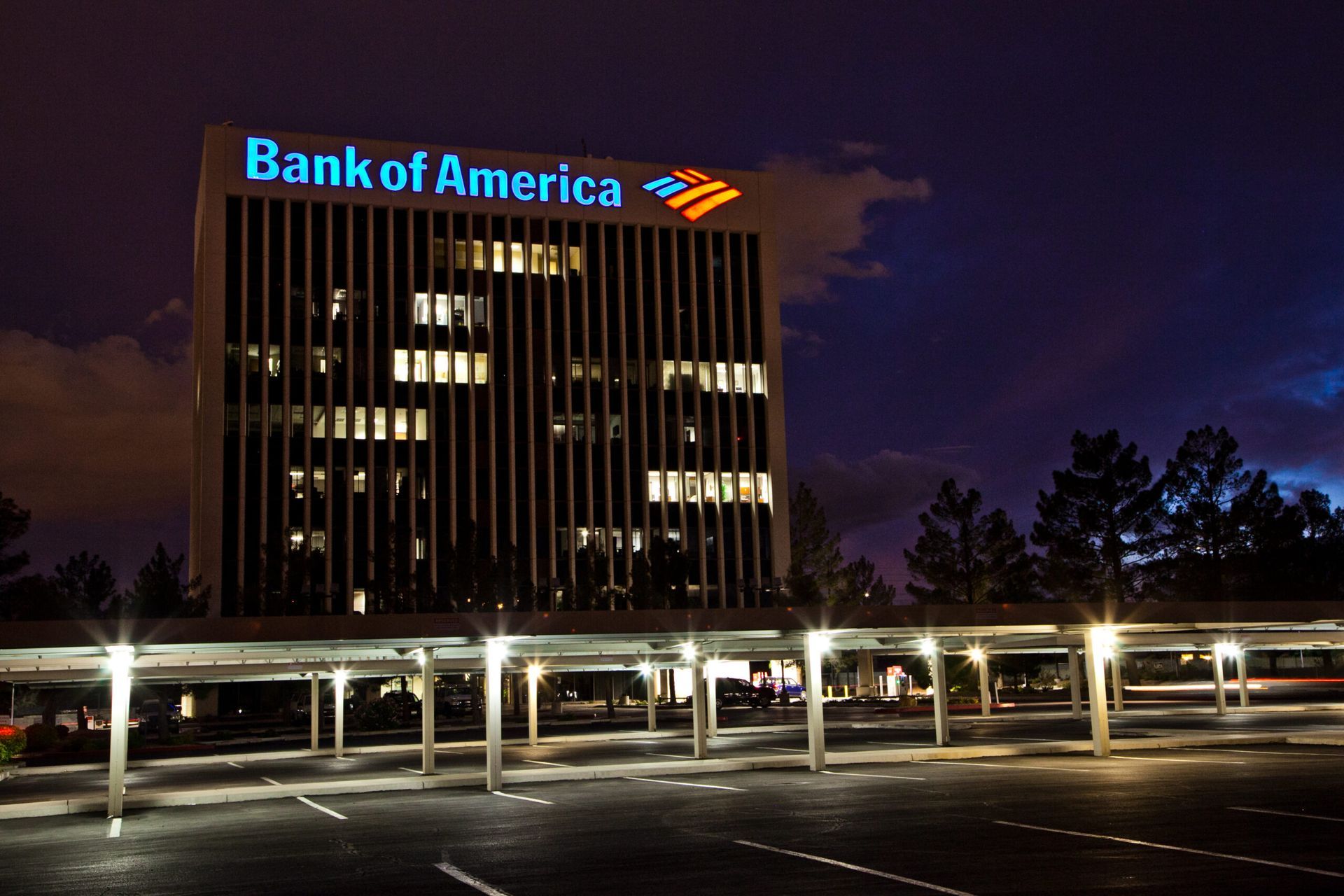 Bank of America office building lit at night with illuminated parking lot and dark sky