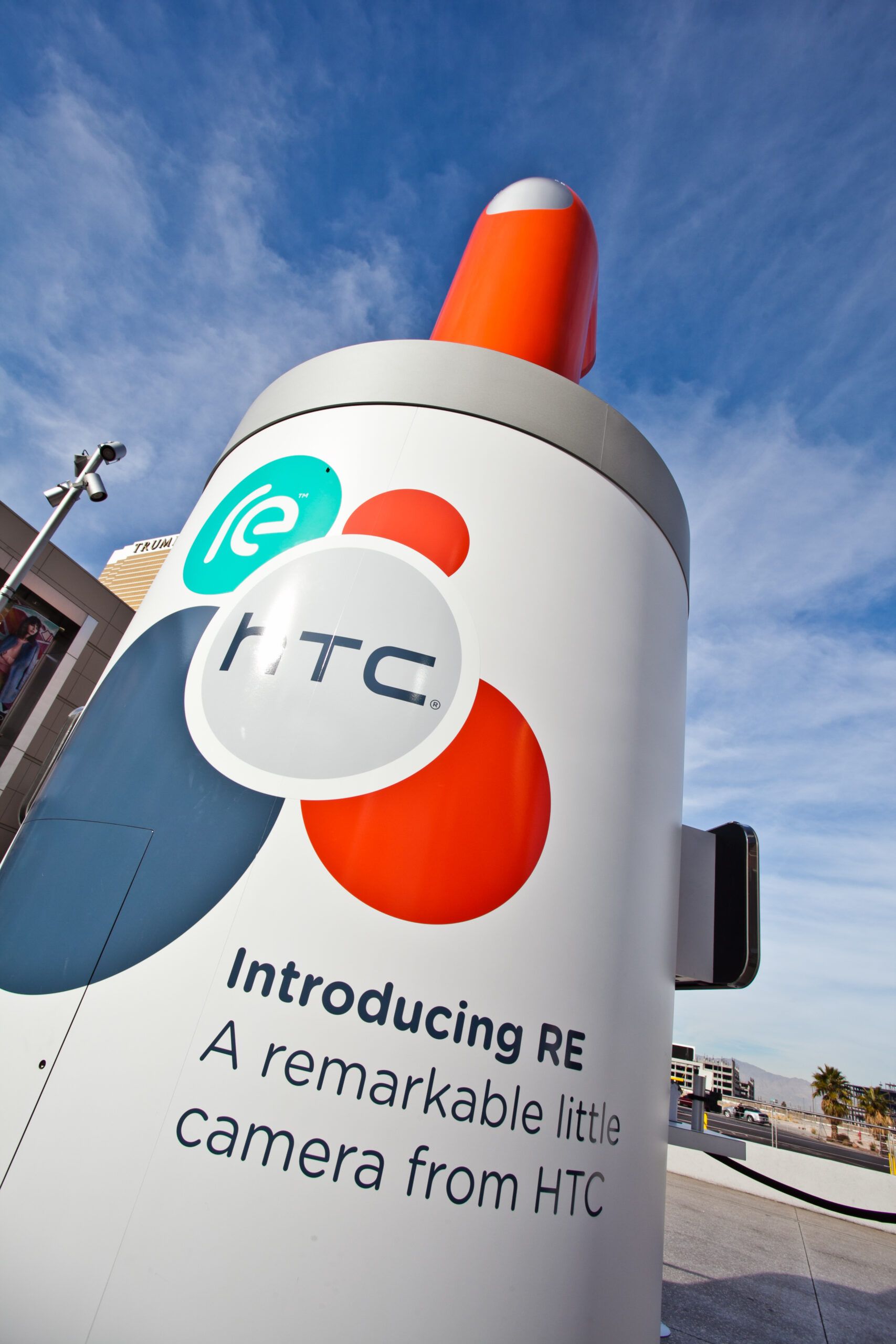 Large white TTC camera-shaped display outdoors with orange and teal — advertising photography