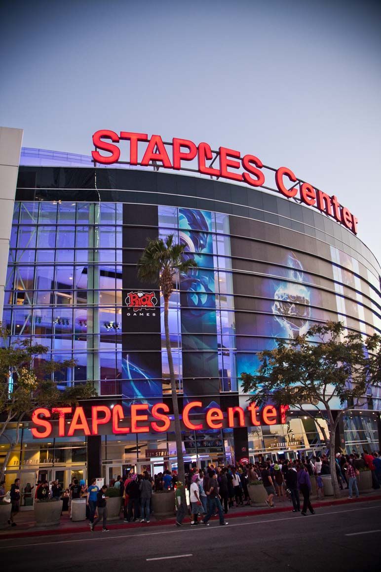 Staples Center entrance at dusk with red neon signage and people gathered outside — convention and event photography