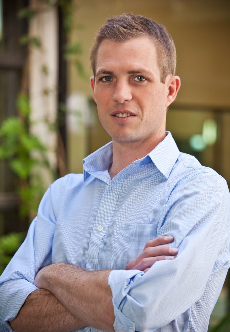 Man in a light blue shirt standing with arms crossed in a blurred indoor hallway — Las Vegas portrait photography