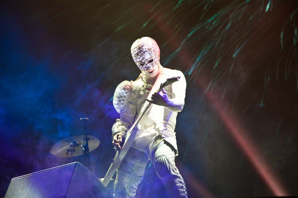Musician playing guitar under purple stage lights, with colorful streaks in the background — convention and event photography