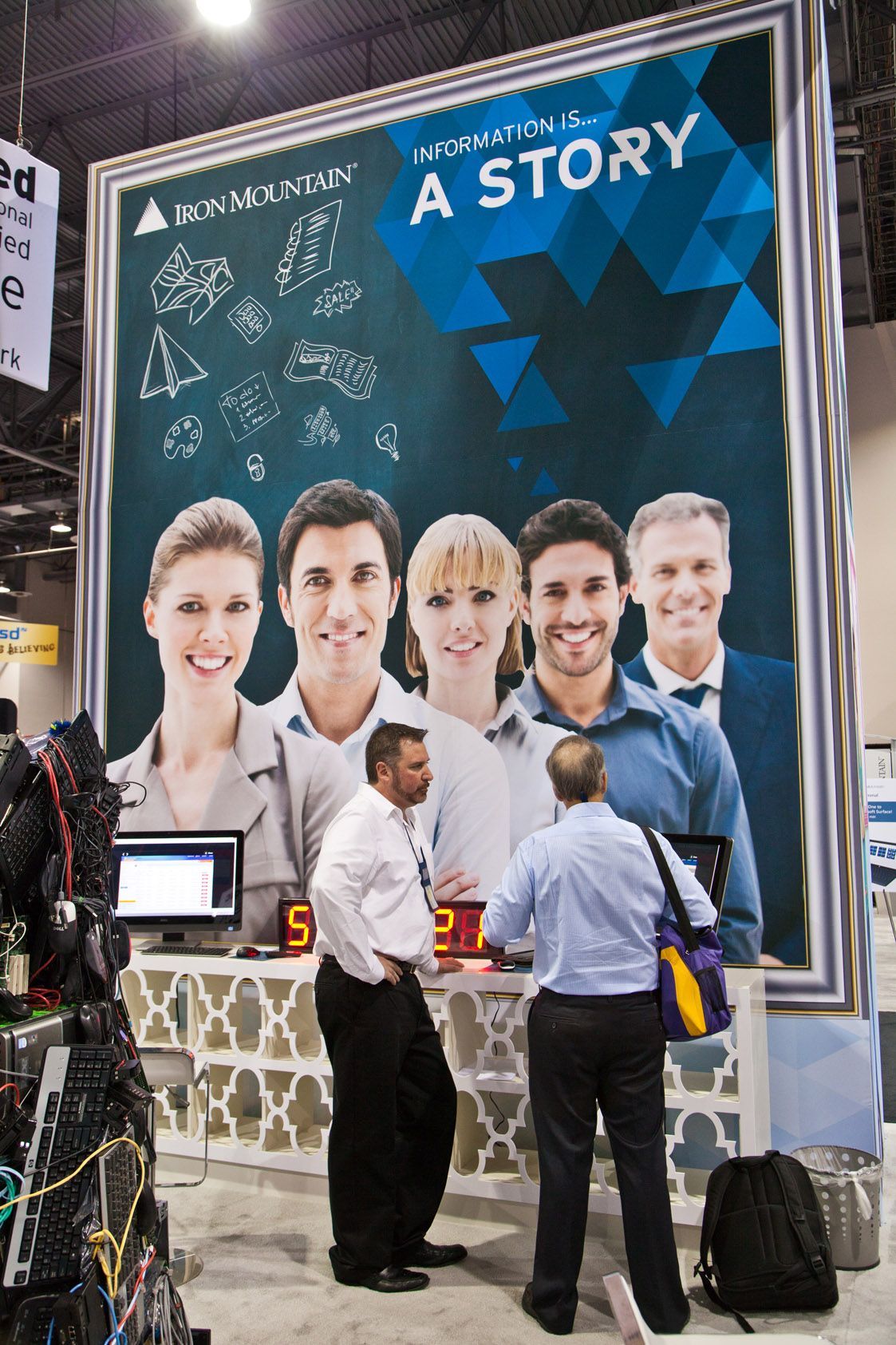 Trade show booth with a large “A STORY” banner and several people standing in front of it
