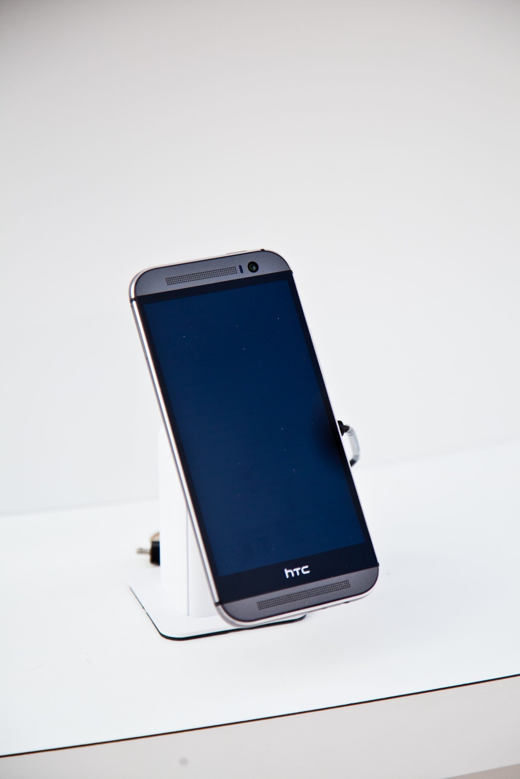 Smartphone on a white display stand with a dark blue screen, angled against a white background
