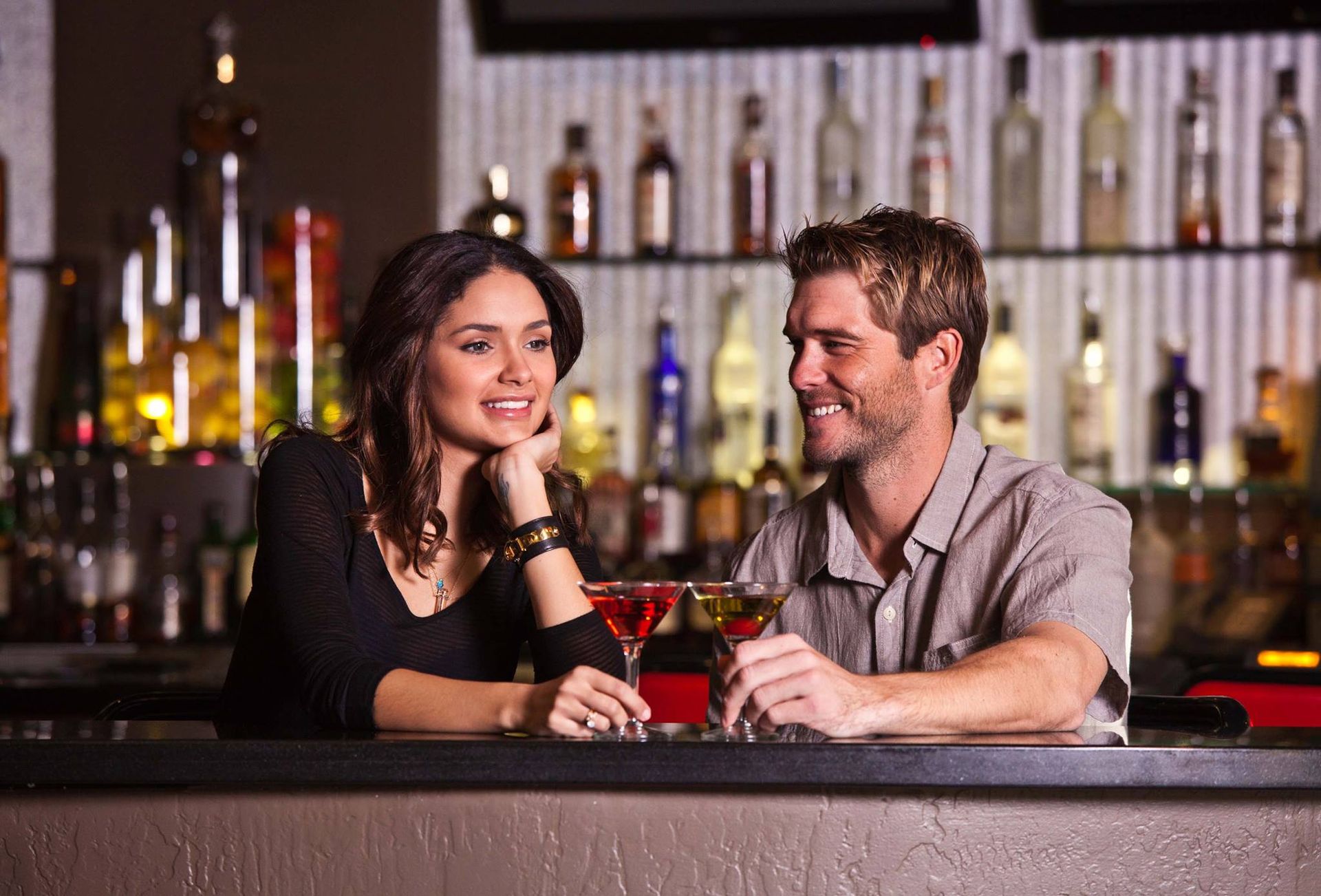 Two people smiling at a bar, holding red cocktails with — Las Vegas multi-family photography