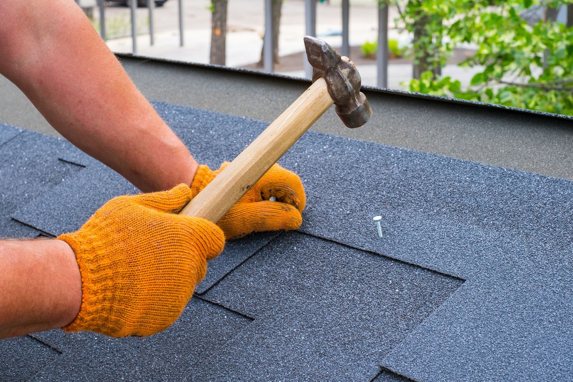 A man is hammering a nail into a roof with a hammer. - Verona, VA - Quality Enterprises
