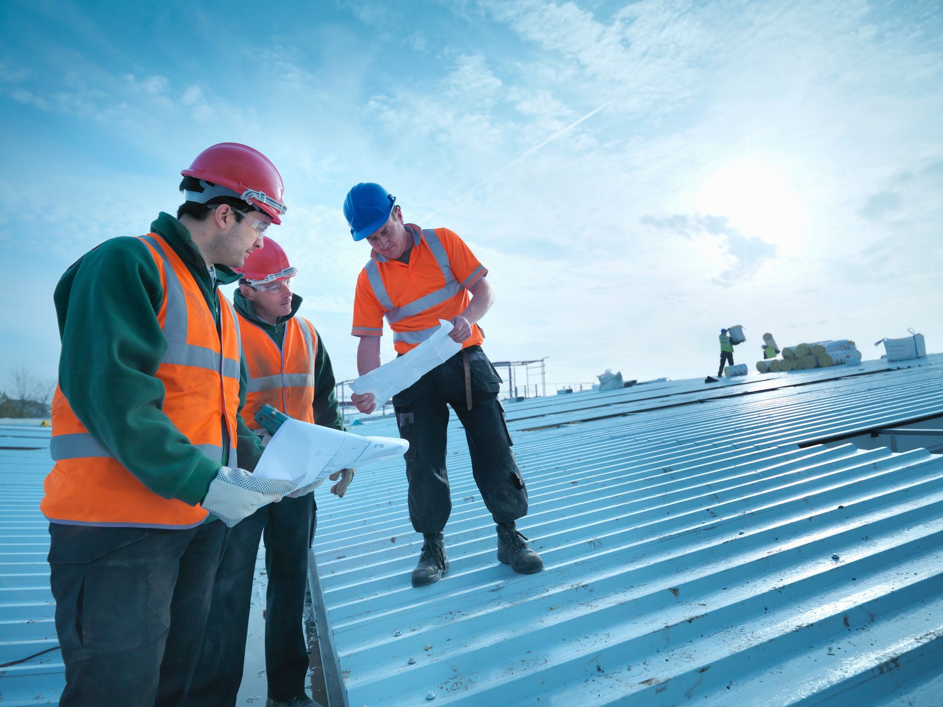 Three men in hard hats and safety vests, representing a commercial roofing inspection contractor.