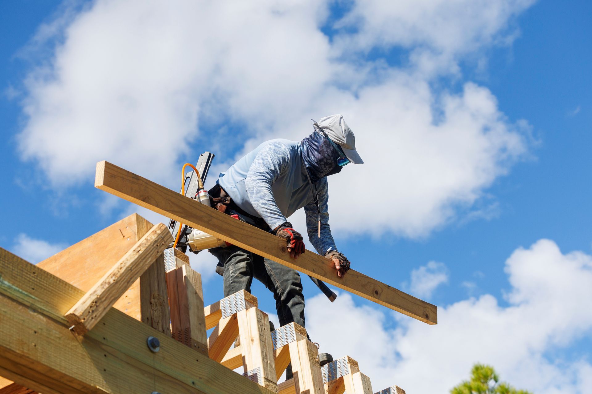 Construction worker installing lumber on a roof, blue sky background. Construction worker installing lumber on a roof, blue sky background.