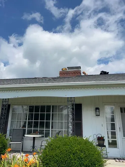 A white house with a roof that has a chimney on it.