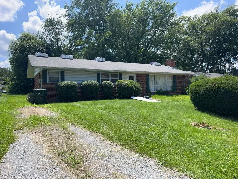 A house with a lot of grass and bushes in front of it.