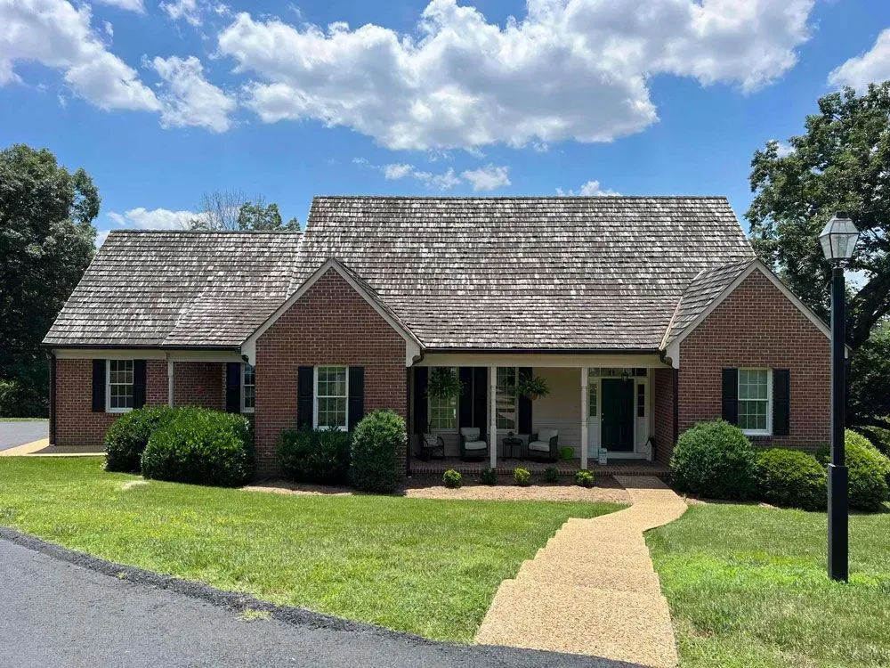 A brick house with a shingle roof and a porch