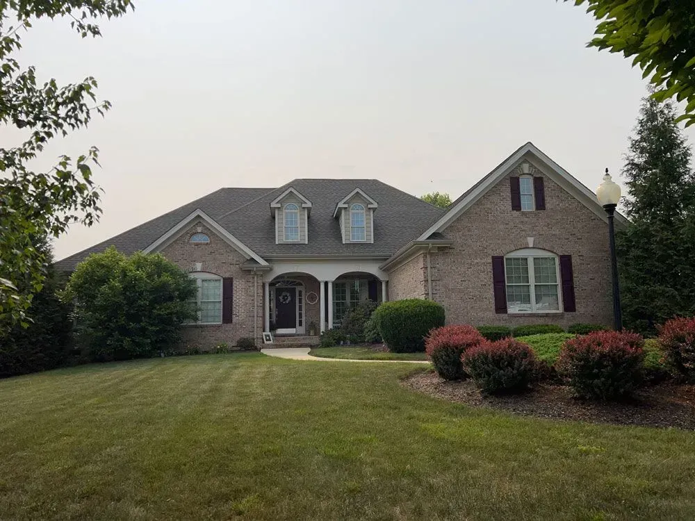 A large brick house with a large lawn in front of it