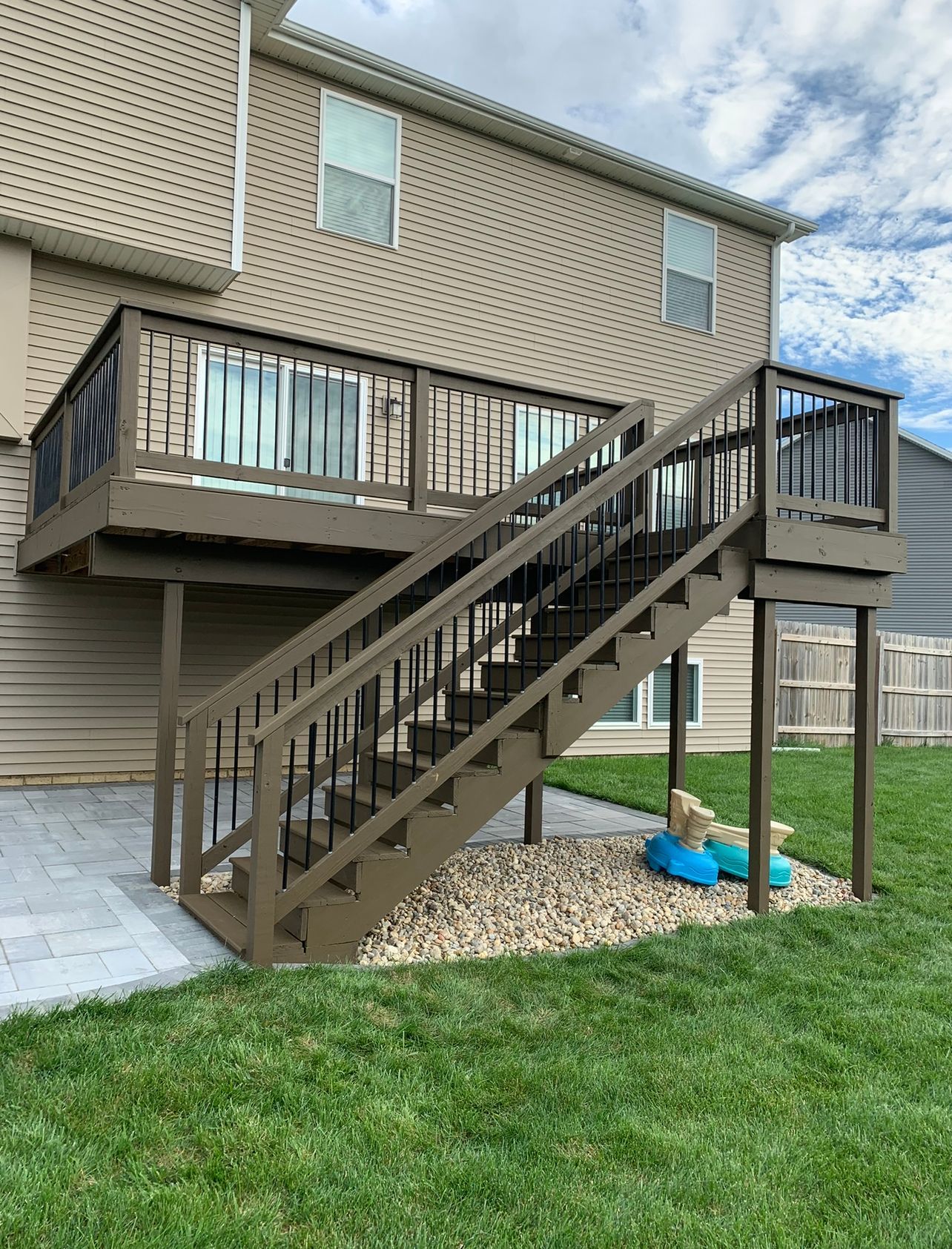 A deck with stairs leading up to it and a house in the background.