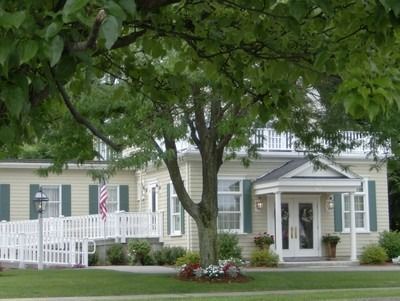 Gray house with white trim, front porch, and a large tree in the yard