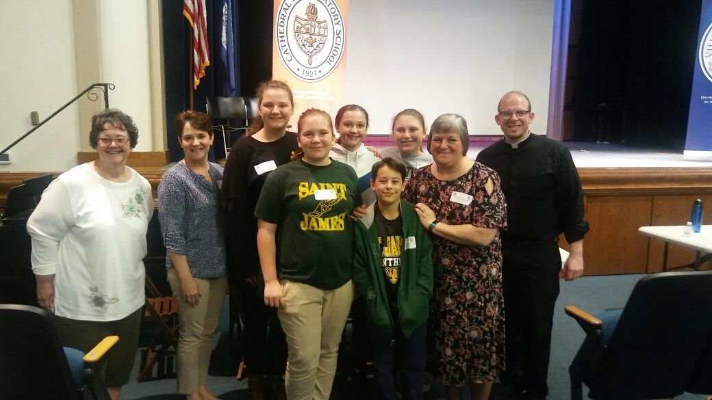 A group of people posing for a picture with one wearing a shirt that says james