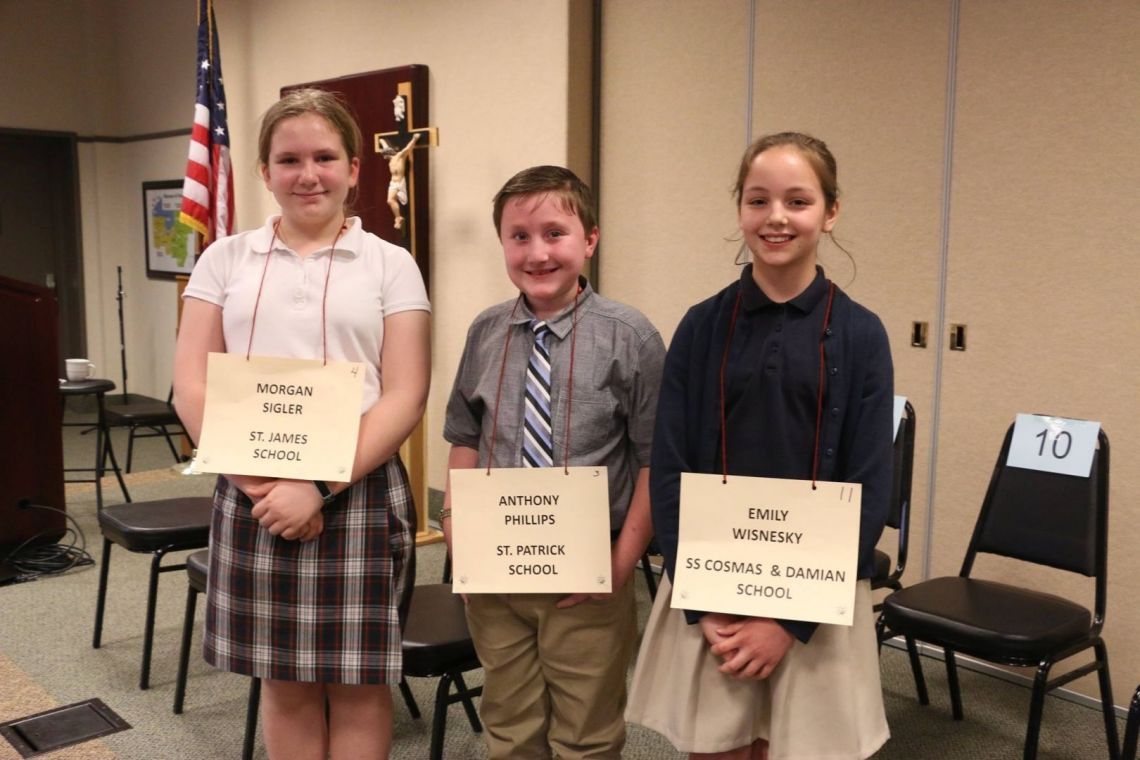 A boy and two girls holding signs that say ' i am a catholic school '
