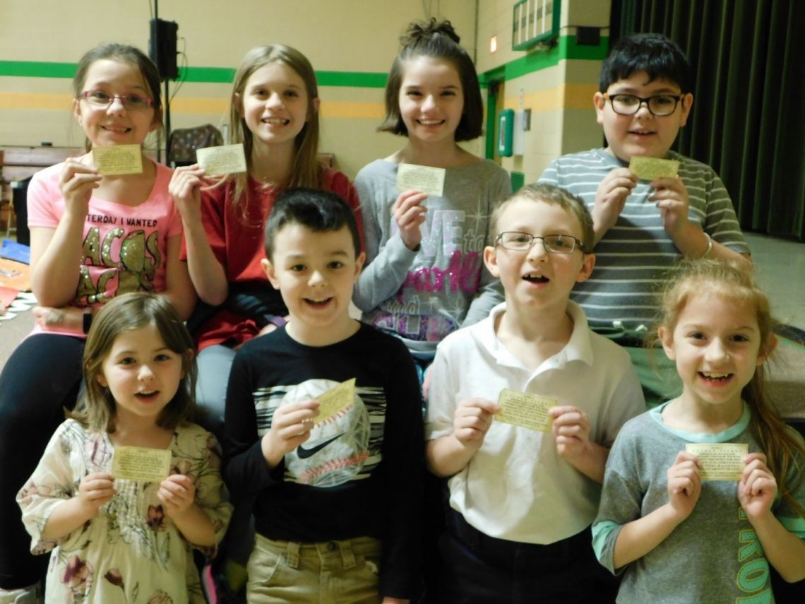 A group of children are posing for a picture while holding cards