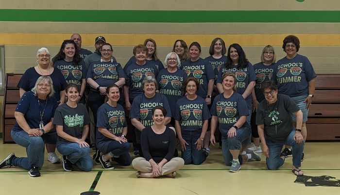 A group of people posing for a picture with one wearing a shirt that says ' school ' on it