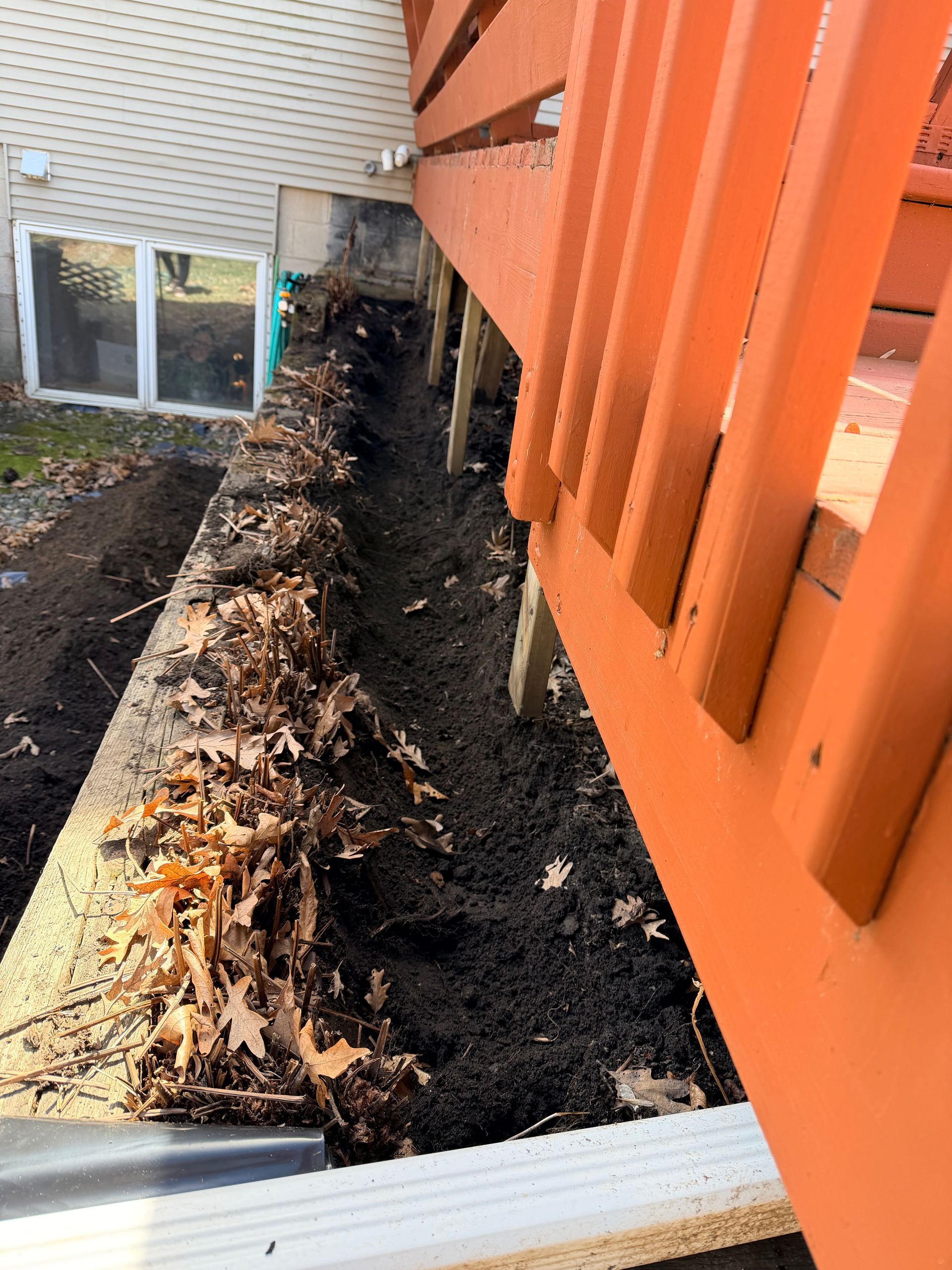 Fire-damaged narrow walkway beside an orange staircase and railing, with charred debris along the edge.