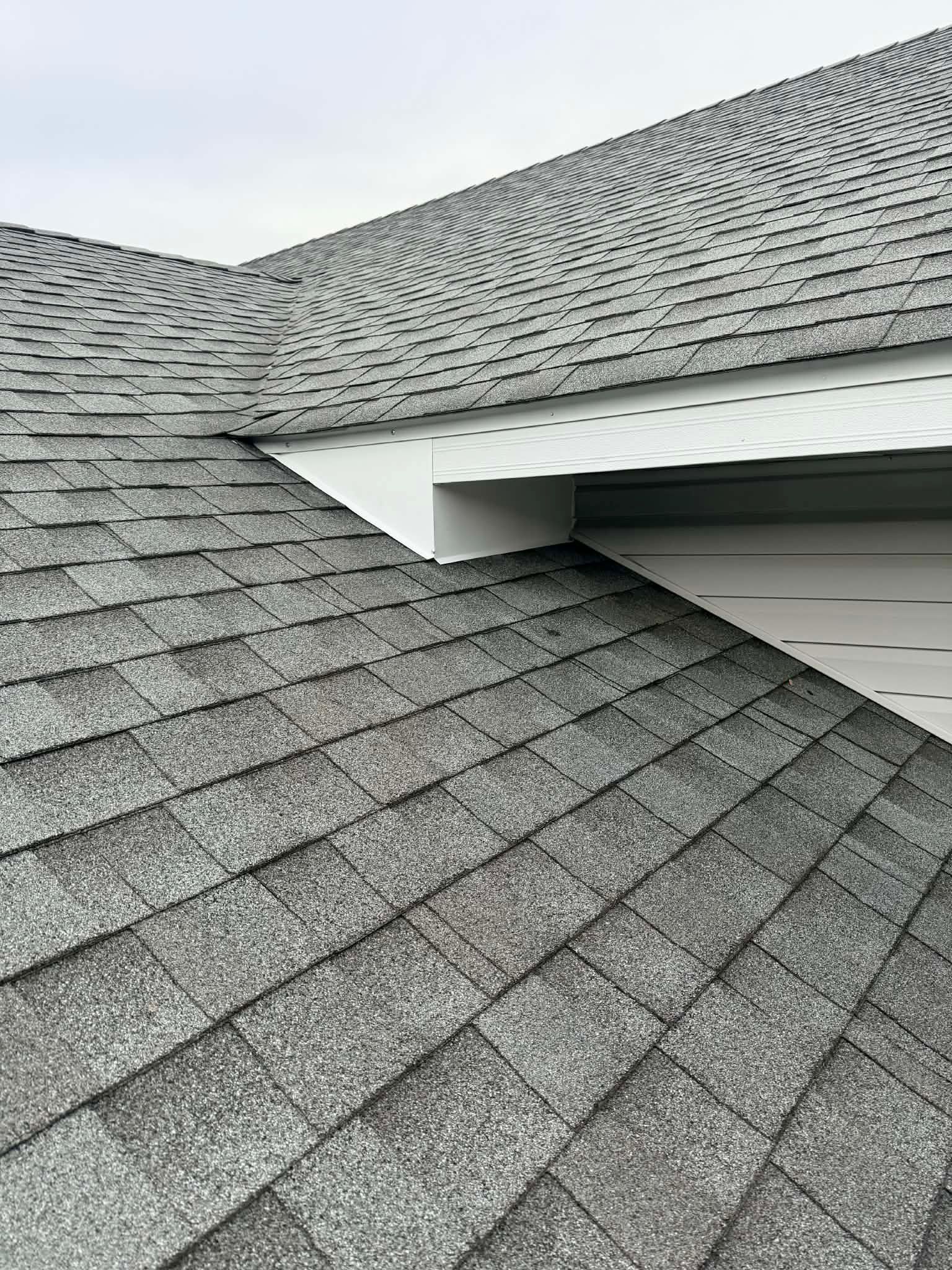 Gray shingled roof with a valley and white soffit on a house