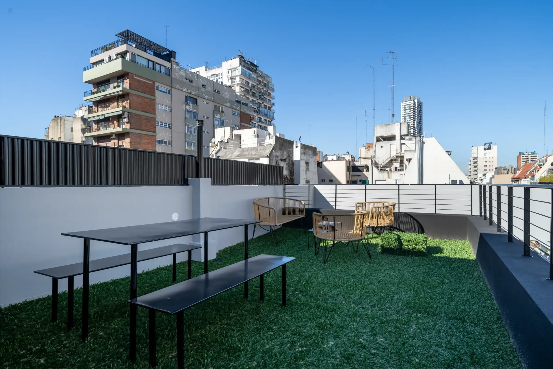 Un jardín en la azotea con una mesa de picnic y bancos.
