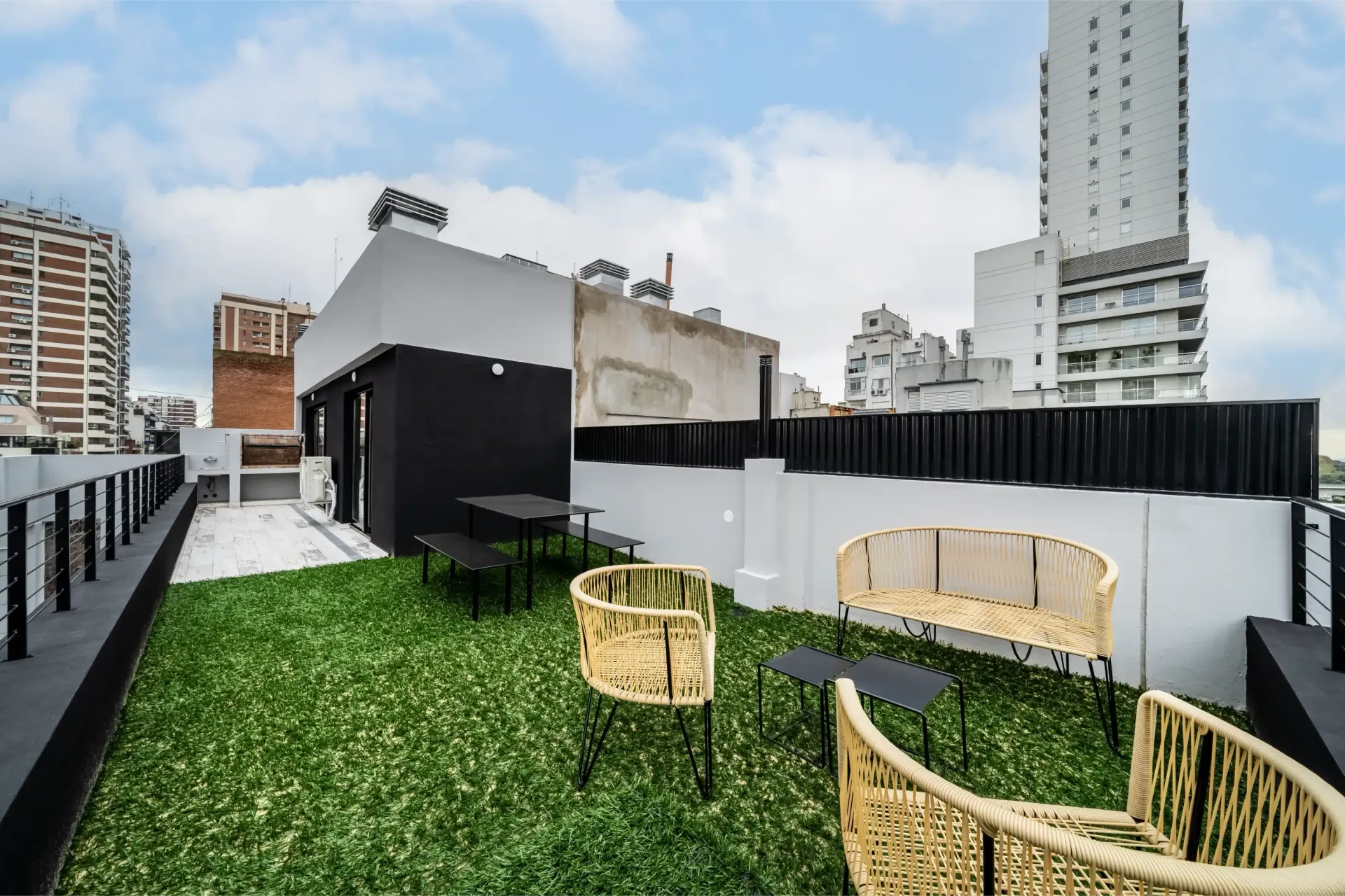 Un jardín en la azotea con sillas, mesas y una mesa.