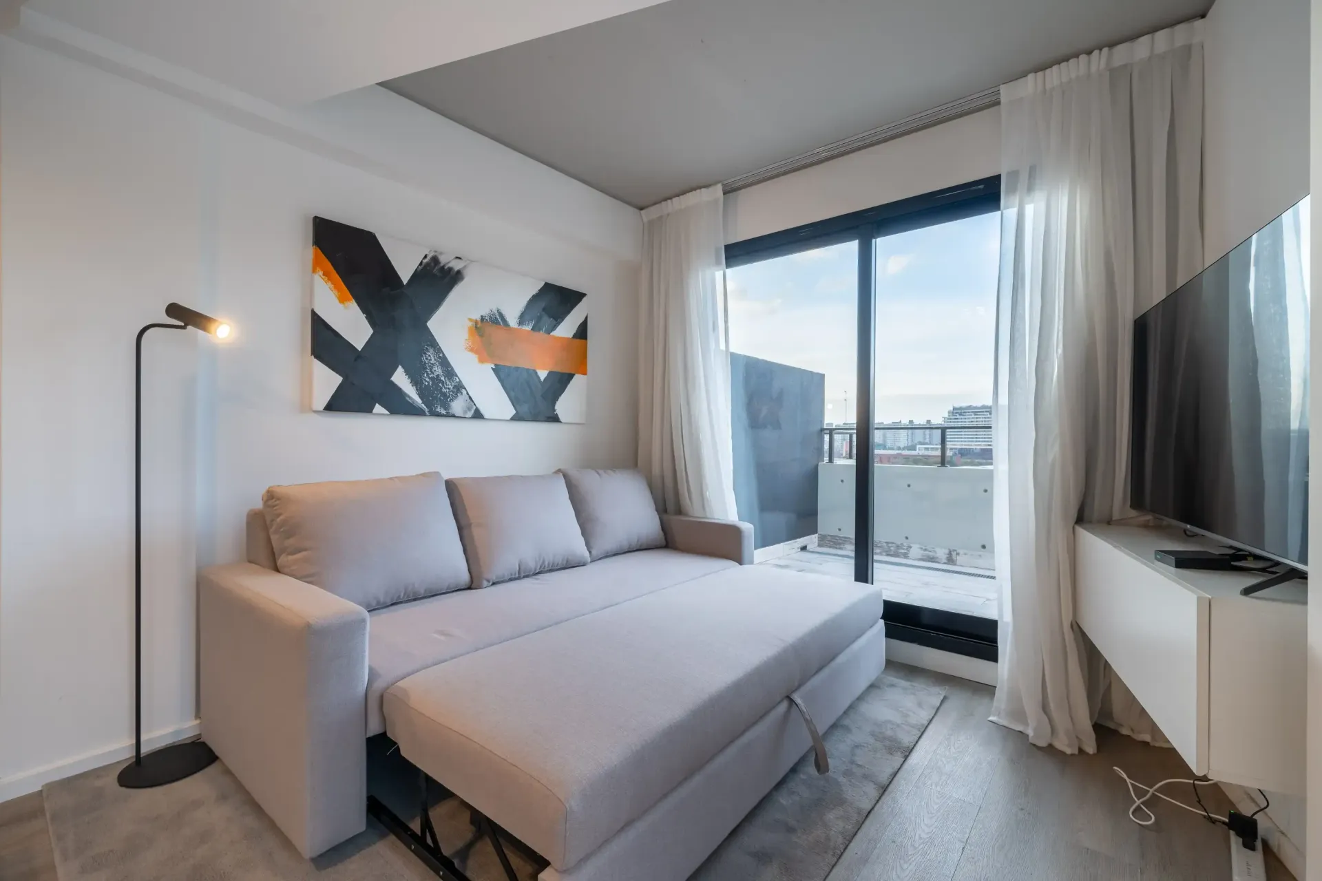 Una sala de estar con un sofá y un televisor de pantalla plana.